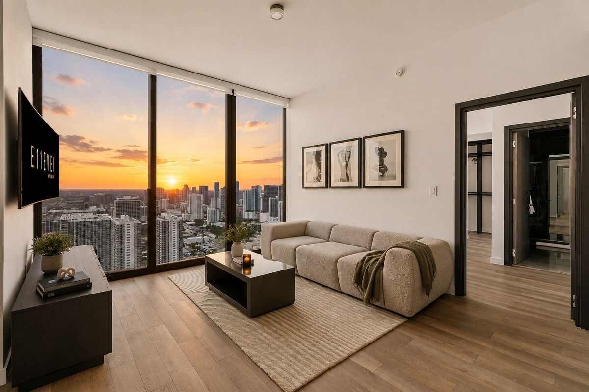 A modern living room with a large window, a sofa, a coffee table, and framed artwork.
