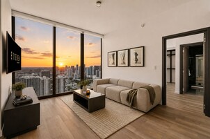 A modern living room with a large window, a sofa, a coffee table, and framed artwork.