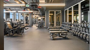 Un gimnasio con equipo de ejercicio, mancuernas y un espejo grande.