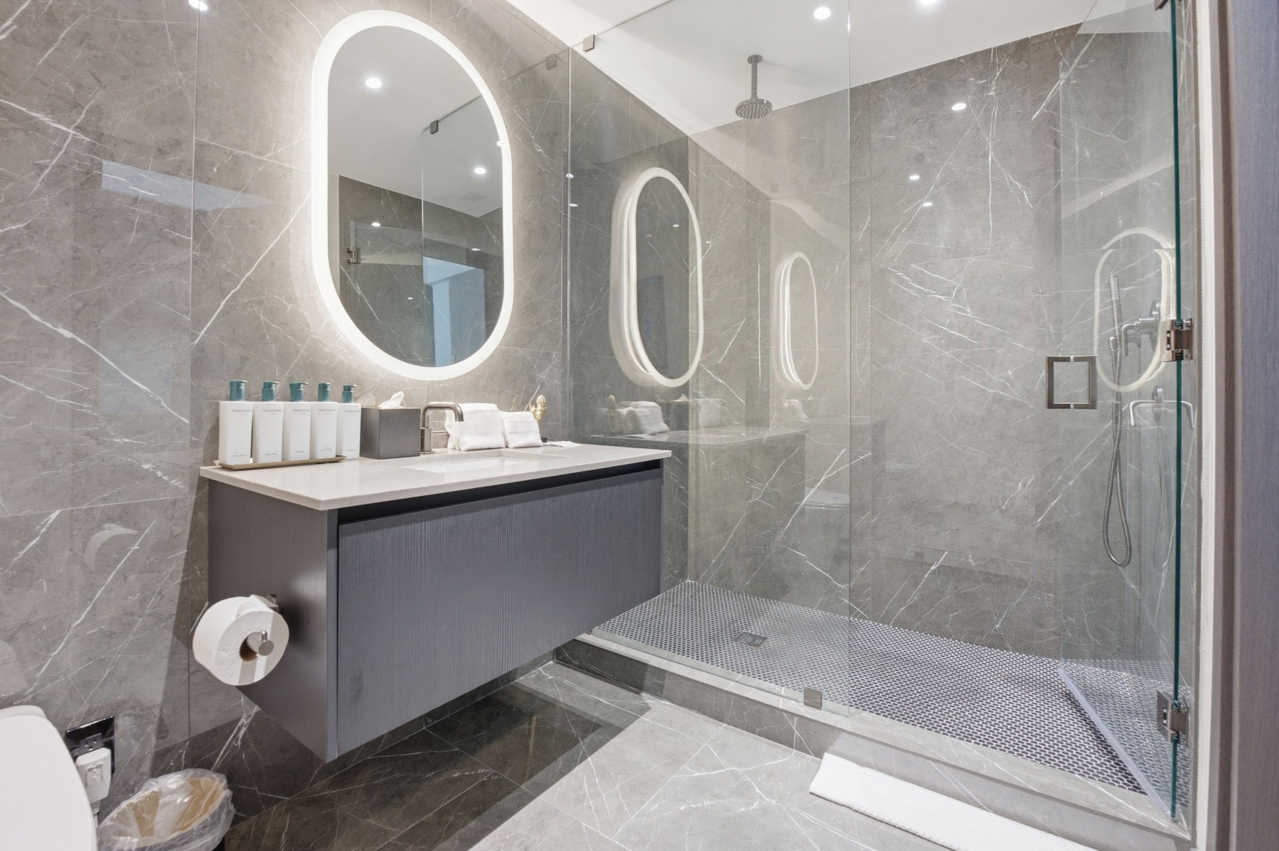 Une salle de bain moderne avec une douche à parois de verre, un meuble-lavabo avec un miroir et des articles de toilette.