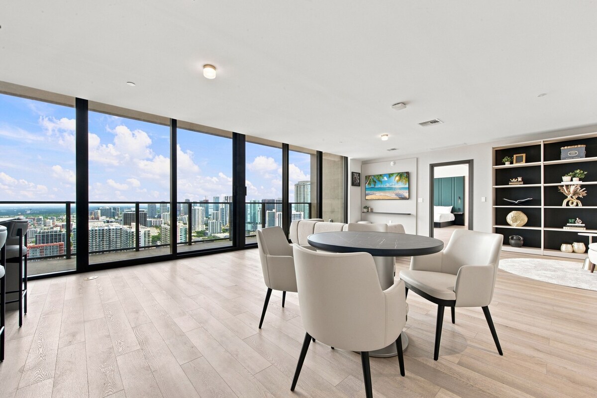 A spacious room with a large window, a round table, and a bookshelf.