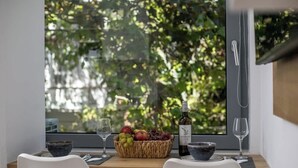 Ein Esstisch mit Obstkorb, einer Weinflasche und zwei Gläsern.