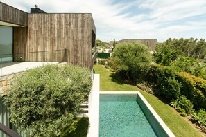 En moderne bygning med træfacade, swimmingpool og velholdt have.