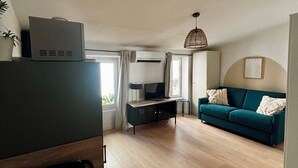 Ett modernt vardagsrum med en soffa, en tv, ett litet bord och en taklampa.
