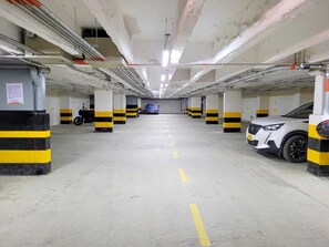 A multi-level parking garage with yellow and black striped pillars, concrete floors, and overhead lighting.