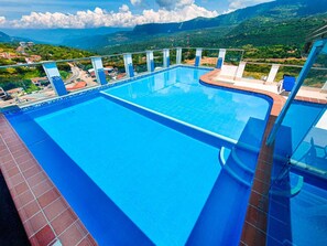 A large outdoor swimming pool with a view of a mountainous landscape.
