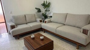 Una sala de estar con un sofá modular, una mesa de centro de madera y una planta en maceta.
