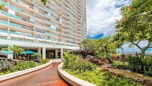 Un hotel de diseño moderno, con un patio central que tiene un paseo de madera, rodeado de abundante vegetación y una fuente de agua.