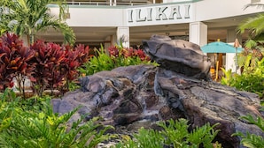 Un hotel con una cascada de roca, abundante vegetación y un letrero que dice "ILIKAI".