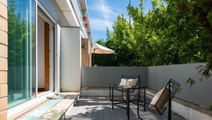 Eine moderne Terrassengestaltung mit Glastür, Tisch und zwei Stühlen.