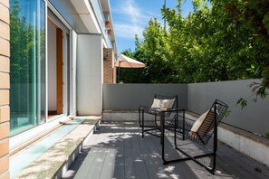 Eine moderne Terrassengestaltung mit Glastür, Tisch und zwei Stühlen.