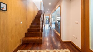 Eine Holztreppe führt zu einer zweiten Etage, einem Flur mit einem gemusterten Teppich und einem großen Fenster mit Ausblick.
