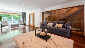 Ein modernes Wohnzimmer mit Sofa, Couchtisch und einer Treppe.