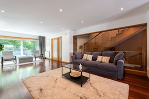 Ein modernes Wohnzimmer mit Sofa, Couchtisch und einer Treppe.