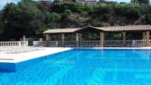 A clear blue pool with white lounge chairs and a covered seating area. - Provençal cottage (Roquebrune-sur-Argens)