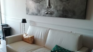 A beige sofa with patterned cushions, a wall-mounted abstract artwork, and a lamp. - Provençal cottage (Roquebrune-sur-Argens)