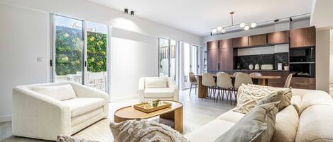 A modern living room with a sofa, coffee table, and a dining area with chairs and a table.