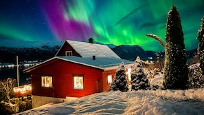 Una casa roja con paisajes nevados y vistas de las auroras boreales.