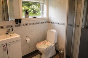 Un baño con inodoro, lavabo y ventana con flores.