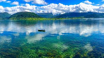 A clear lake with a boat, mountains in the background, and clear water.