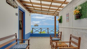 A balcony with wooden furniture, a view of the sea, and a wall with decorative elements. - Maiata Beach 3 (Madeira)