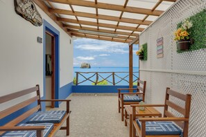 A balcony with wooden furniture, a view of the sea, and a wall with decorative elements. - Maiata Beach 3 (Madeira)