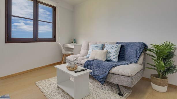 A modern living room with a sofa, a coffee table, a potted plant, and a window with a view of the sky. - Maiata Beach 3 (Madeira)