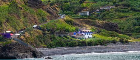 Un village côtier avec des maisons construites sur une colline, une route qui y mène et une côte rocheuse.