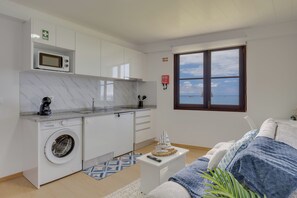 A compact kitchen with a washing machine, a microwave, and a window with a view of the sea. - Maiata Beach 3 (Madeira)