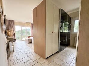 Ein geräumiges Zimmer mit großem Schiebetürenschrank, einem Bett mit Blick und einer Essecke mit Tisch und Stühlen.
