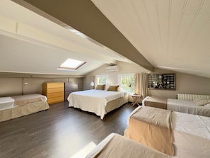 A bedroom with a skylight, a bed, a chest of drawers, a small table, and a radiator. - VillaSerenita Heated Pool, Jacuzzi, Ping Pong (ALATA)