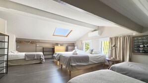 Een kamer met twee bedden, een bureau, een stoel, een kledingkast en een dakvenster.
