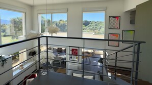 A modern interior with large windows, a staircase, and a view of greenery.