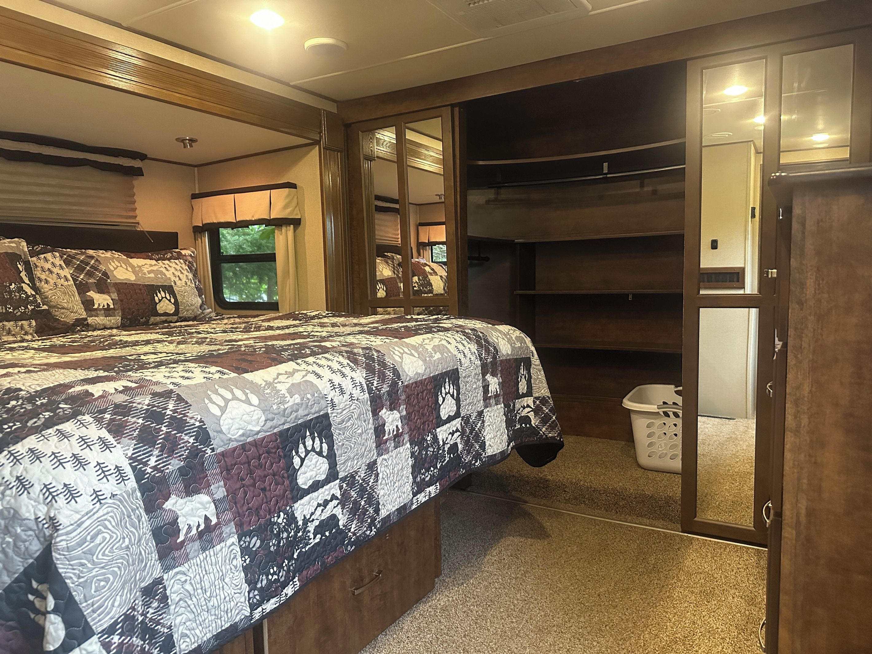 A bedroom with a large bed, a closet with a mirror, and a window with curtains.