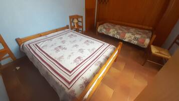Een kamer met een bed, een houten stoel, een bank en een kledingkast van hout.