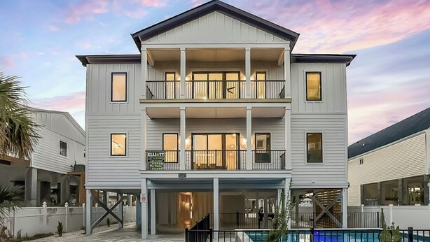 A two-story building with a balcony on the second floor, a covered entrance, and a swimming pool in the foreground. - Sleeps 28-Blue Whale-Pool-12 Bedrooms & 4 Kitchens (North Myrtle Beach)