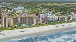 A coastal cityscape with a beachfront hotel featuring multiple high-rise buildings, a sandy beach, and a view of the ocean. - Sleeps 28-Blue Whale-Pool-12 Bedrooms & 4 Kitchens (North Myrtle Beach)