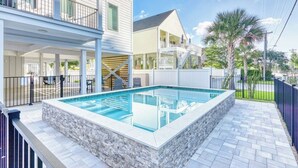 A rectangular swimming pool with a stone border, surrounded by a paved patio. - Sleeps 28-Blue Whale-Pool-12 Bedrooms & 4 Kitchens (North Myrtle Beach)