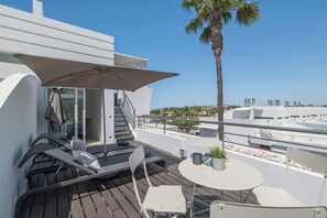 Ein Balkon mit Tisch, Stühlen, Sonnenschirm und Meerblick.