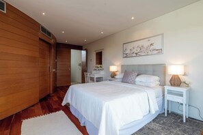 A bedroom with a large bed, bedside tables with lamps, a desk, and a wooden wardrobe. - 2-Bedroom Apartment with Stunning Sea Views in Vale do Lobo / Dounas Douradas (Loulé)