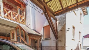 Une voiture est garée sous un abri, avec un bâtiment en arrière-plan.
