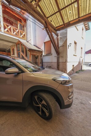 A car parked under a covered area with a building in the background. - Vacation Rental in the Old Wine Cellar, ideally located in Central Alsace (Epfig)