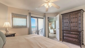 A bedroom with a bed, a dresser, a ceiling fan, and a view of the balcony. - 🐟😍Direct Ocean Front, Poolside Play, Panoramic Scene - Seascape Towers 1123🌴 (New Smyrna Beach)