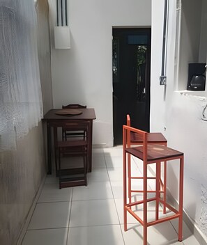 A small, enclosed space with a table and chairs, a door, and a wall-mounted light fixture.