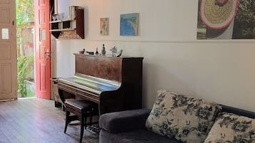 Quarto com piano, sofá e pintura na parede.