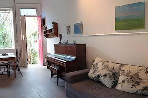 Una sala de estar con un piano, un sofá, una mesa de comedor y sillas.
