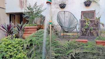 Um jardim com um elemento de água, plantas em vasos e uma cadeira.