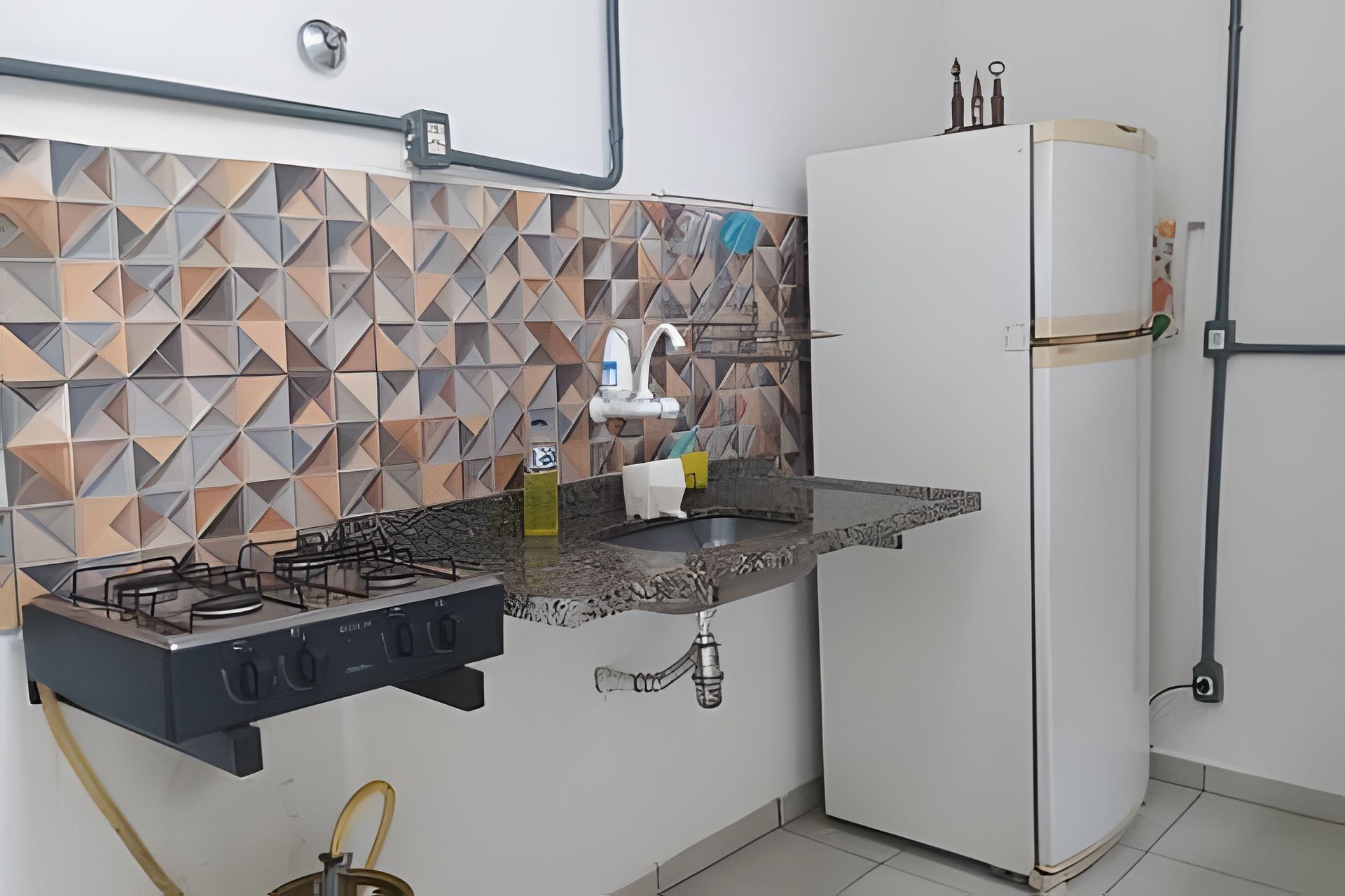 A kitchen with a gas stove, a sink, and a refrigerator.