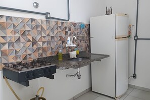 A kitchen with a gas stove, a sink, and a refrigerator.