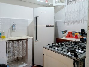 Una cocina con refrigerador, pileta y estufa.